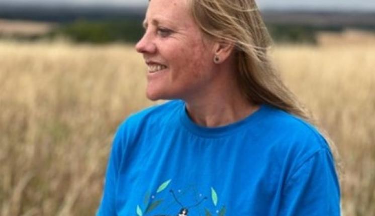 Zoe Randle, smiles in a field wearing a blue top