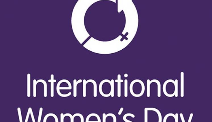 International Women's Day logo. Purple background against white text, with a circular logo.