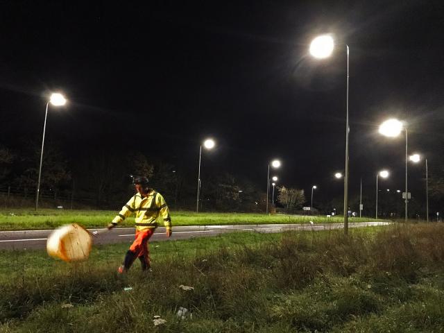 a researcher in a field at night lit by LED streetlights