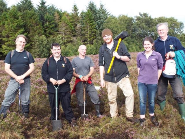 A group of scientists stand with shovels and tools in a bog