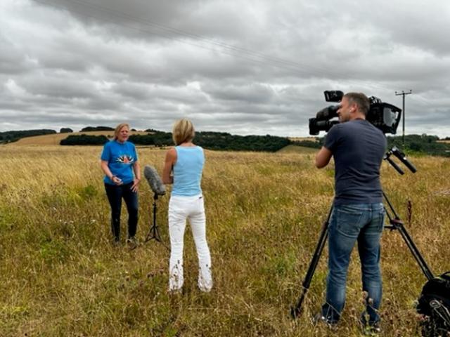 Zoe, interviewed by a reported and cameraman in a field for Big Butterfly Count